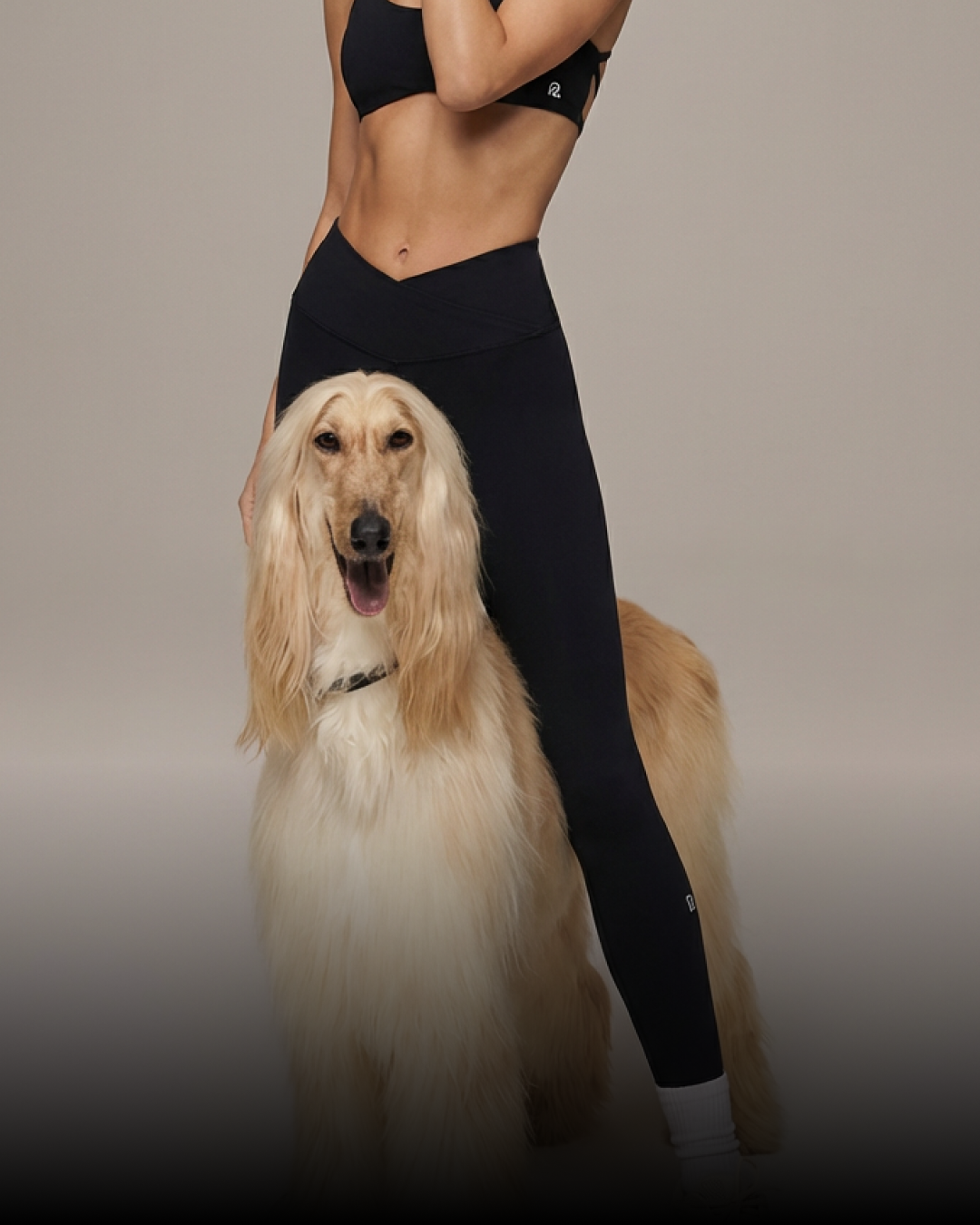 Model in black leggings posing with Afghan hound dog, premium athletic apparel