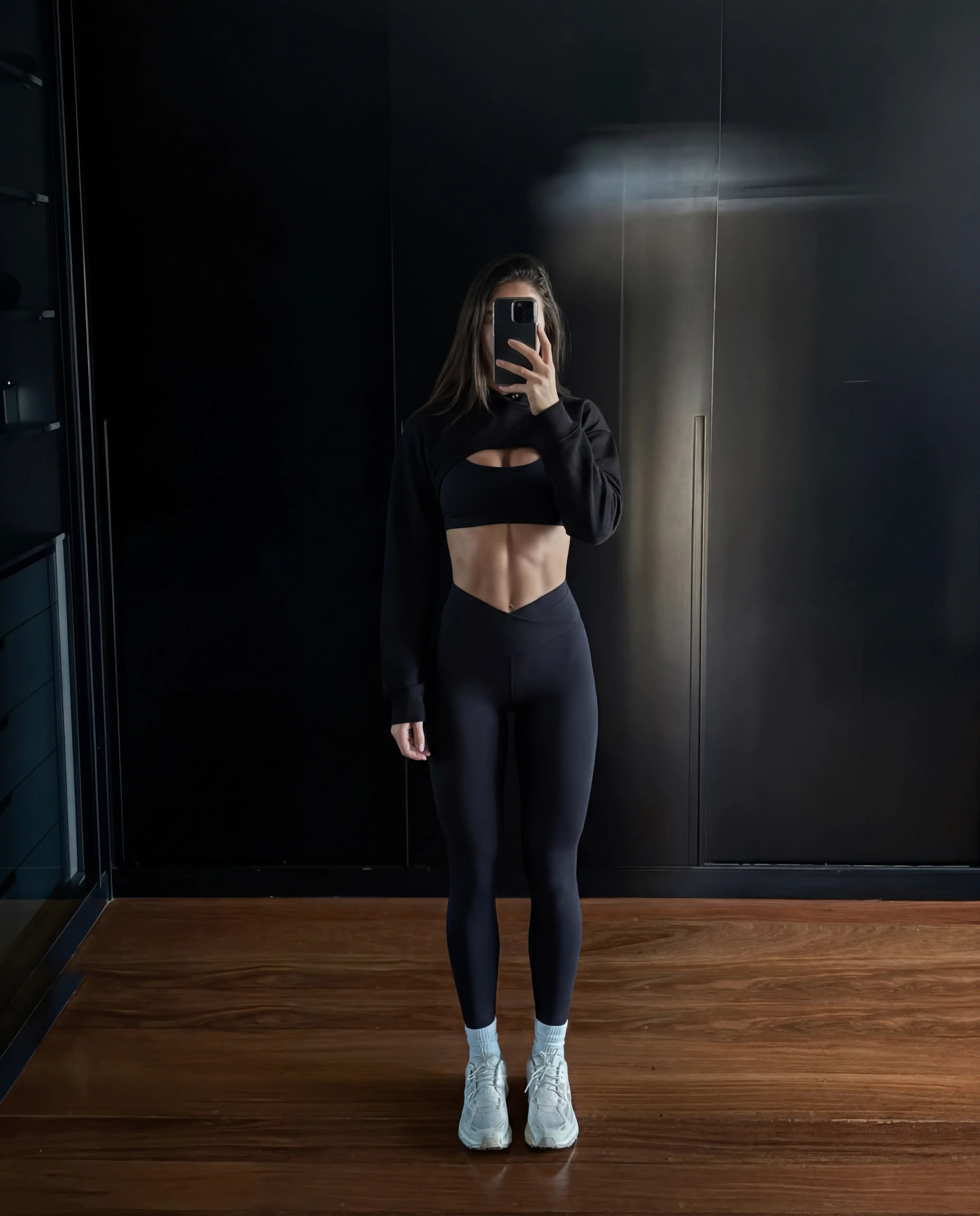 Black cropped hoodie and high waist leggings dark gym full body view
