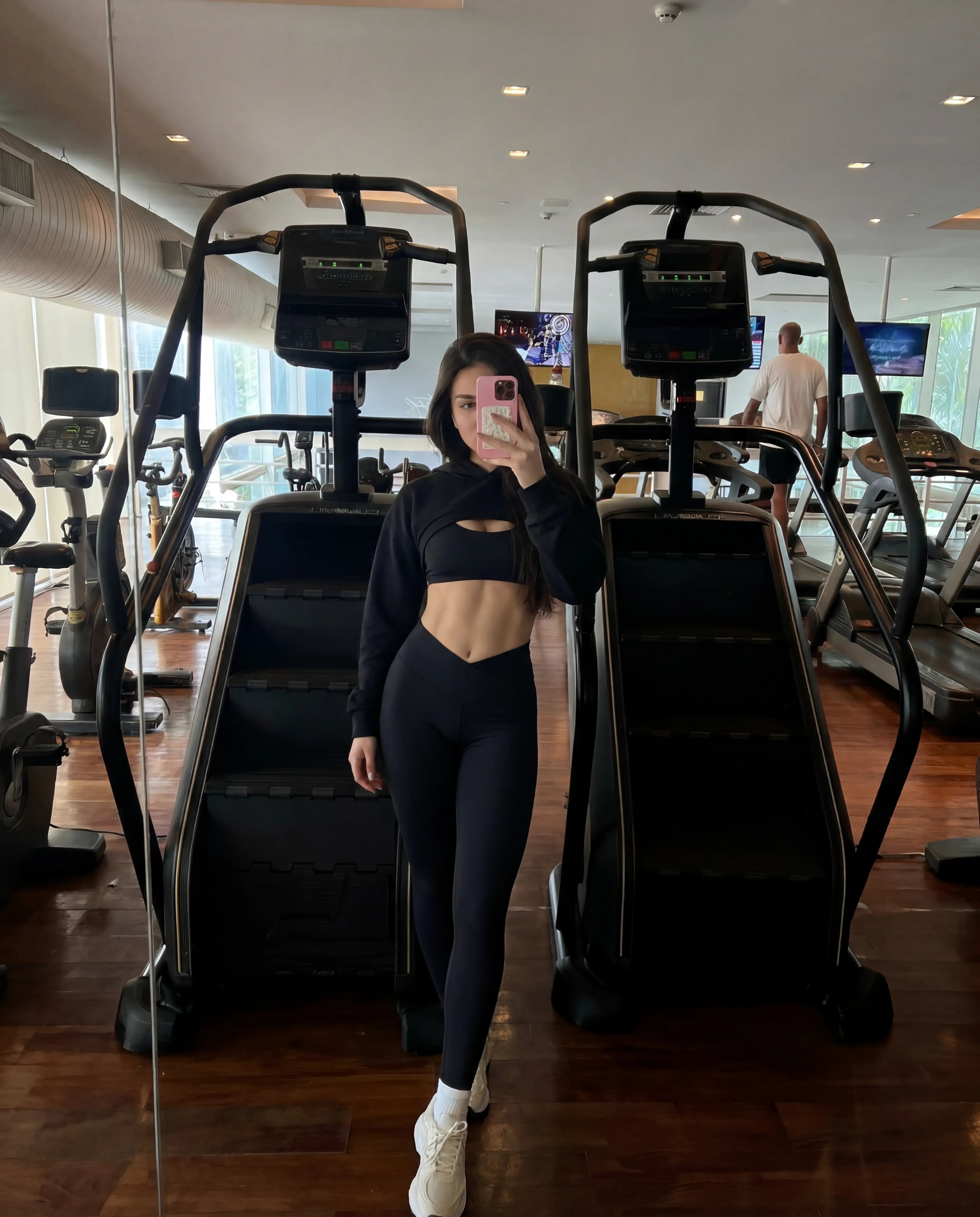 Black cropped hoodie and leggings worn at hotel gym stairmaster mirror