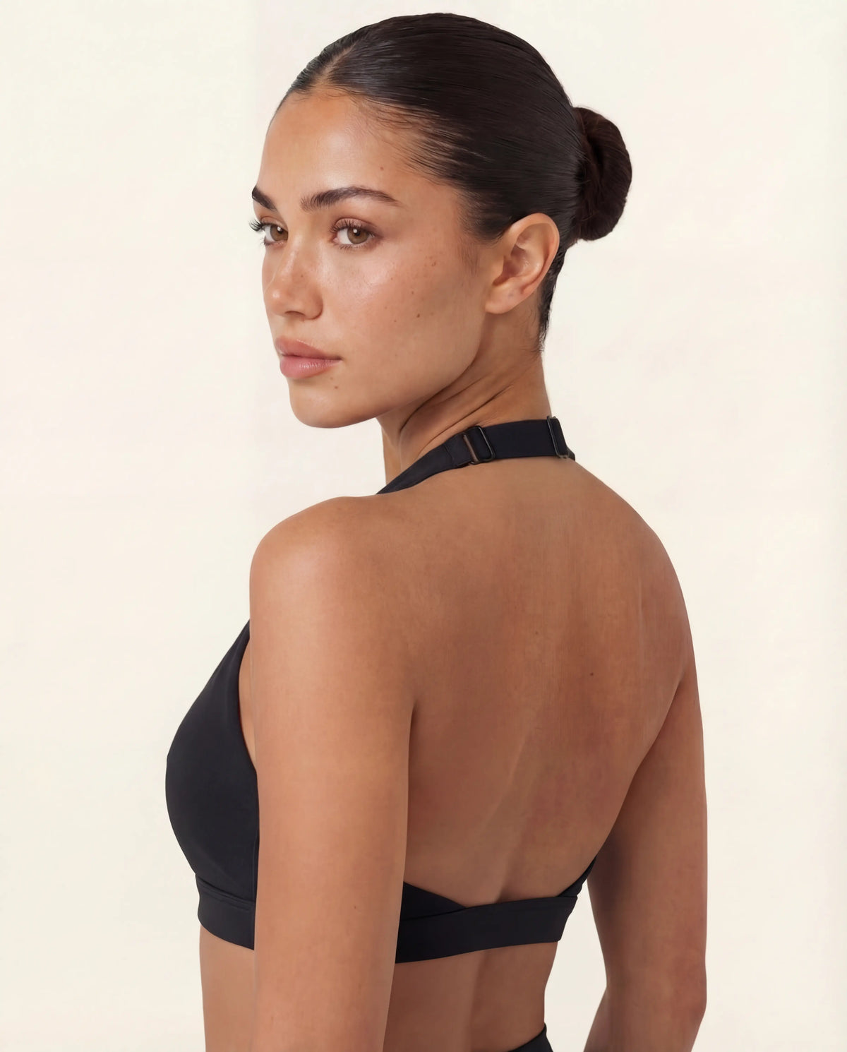 Woman wearing LuxeForm Halter Bra in black during yoga pose, showing supportive fit and freedom of movement