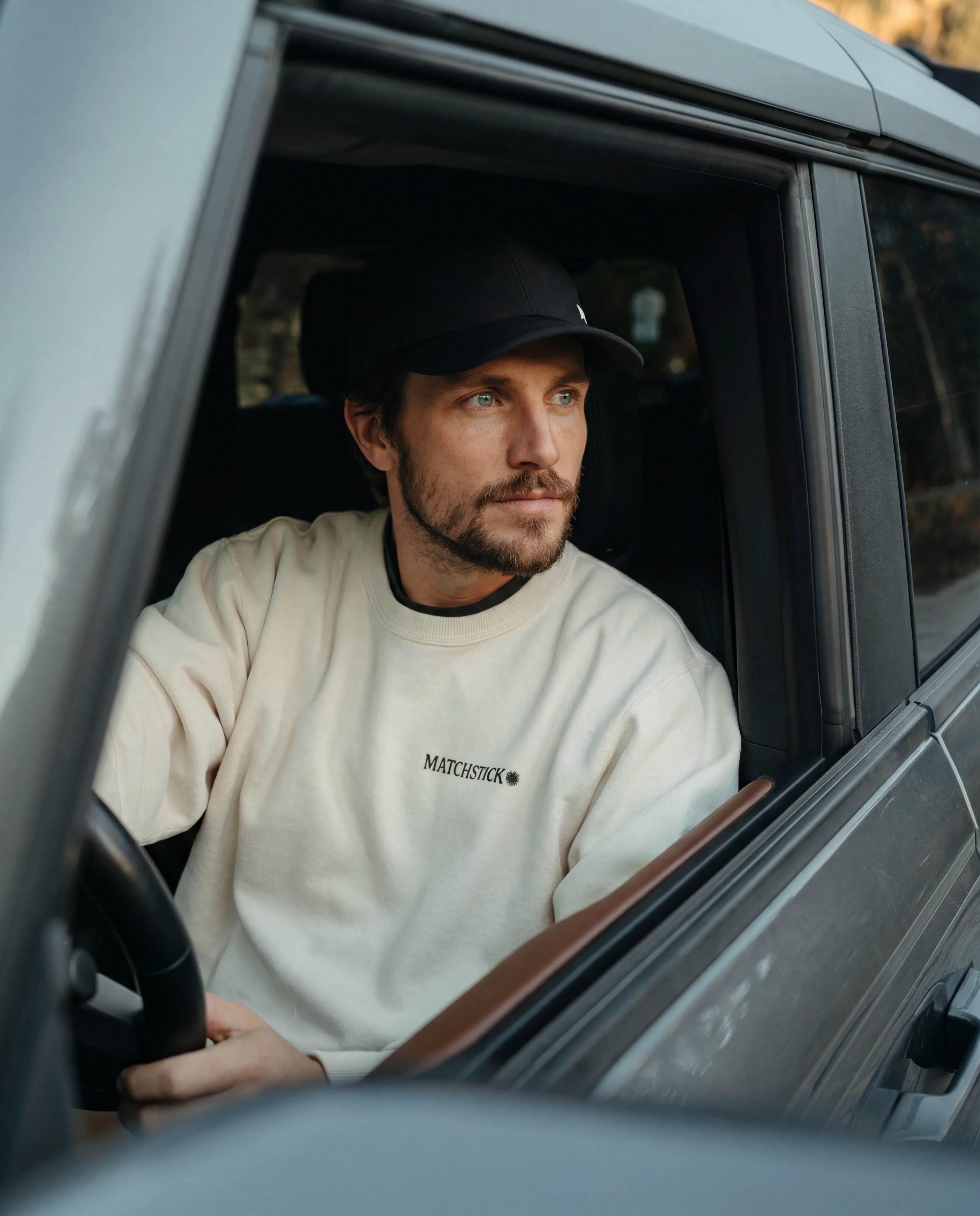 Black running hat with low profile fit worn by man in cream athletic sweatshirt from Runners Athletics