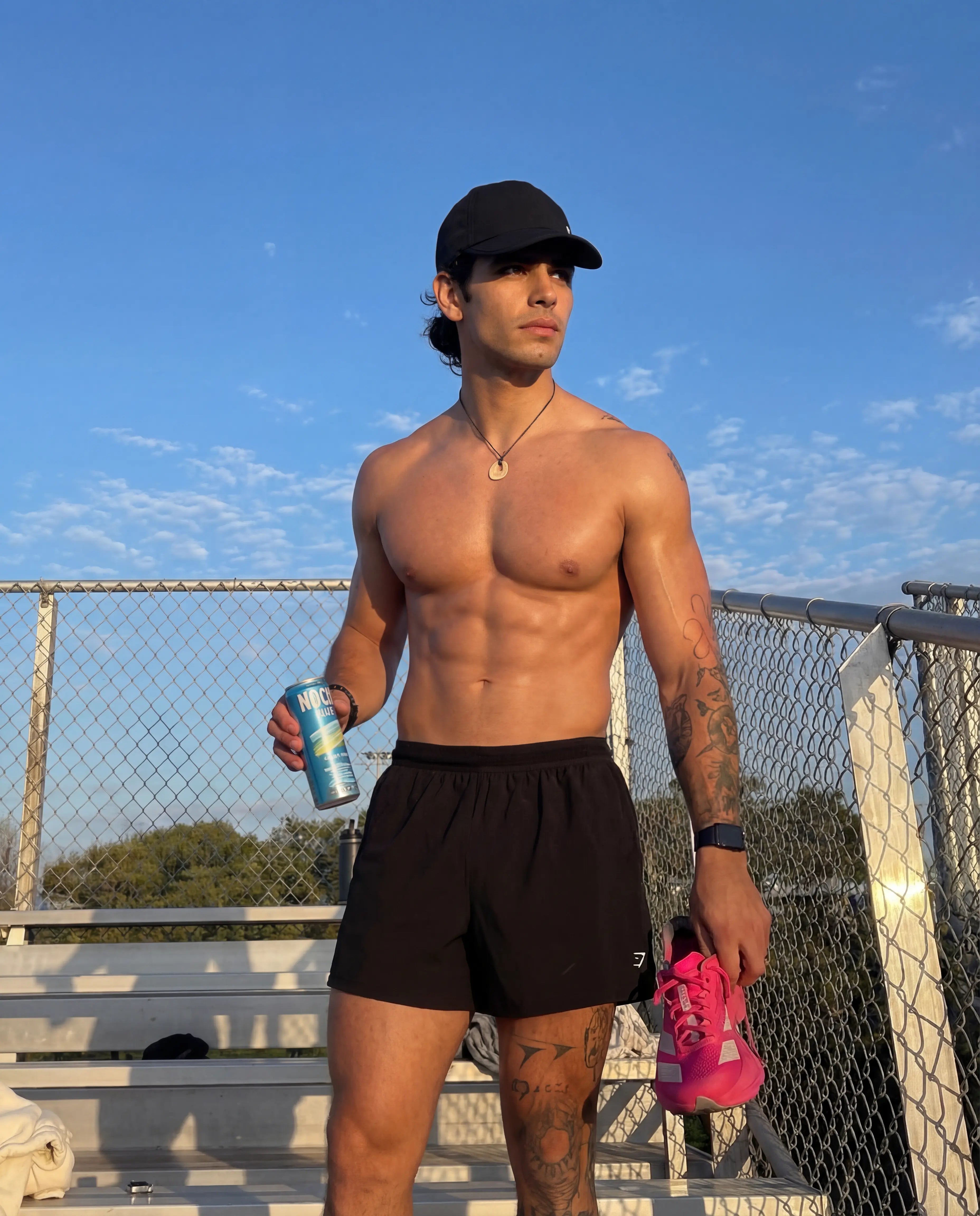 Black running hat worn by man in black athletic shorts at outdoor track from Runners Athletics