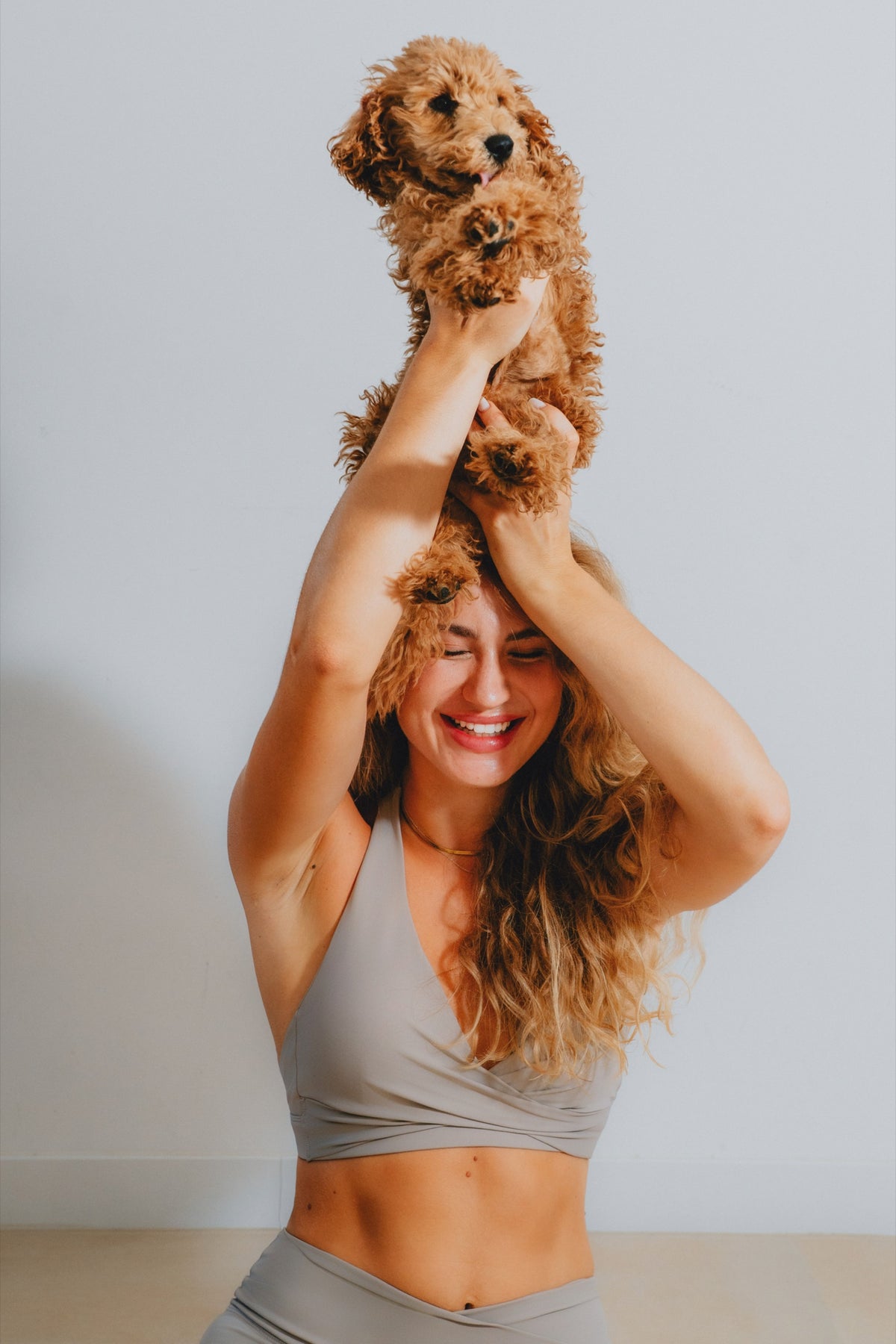 Runner's Athletics model in a mocha taupe sports bra laughing with a puppy between takes