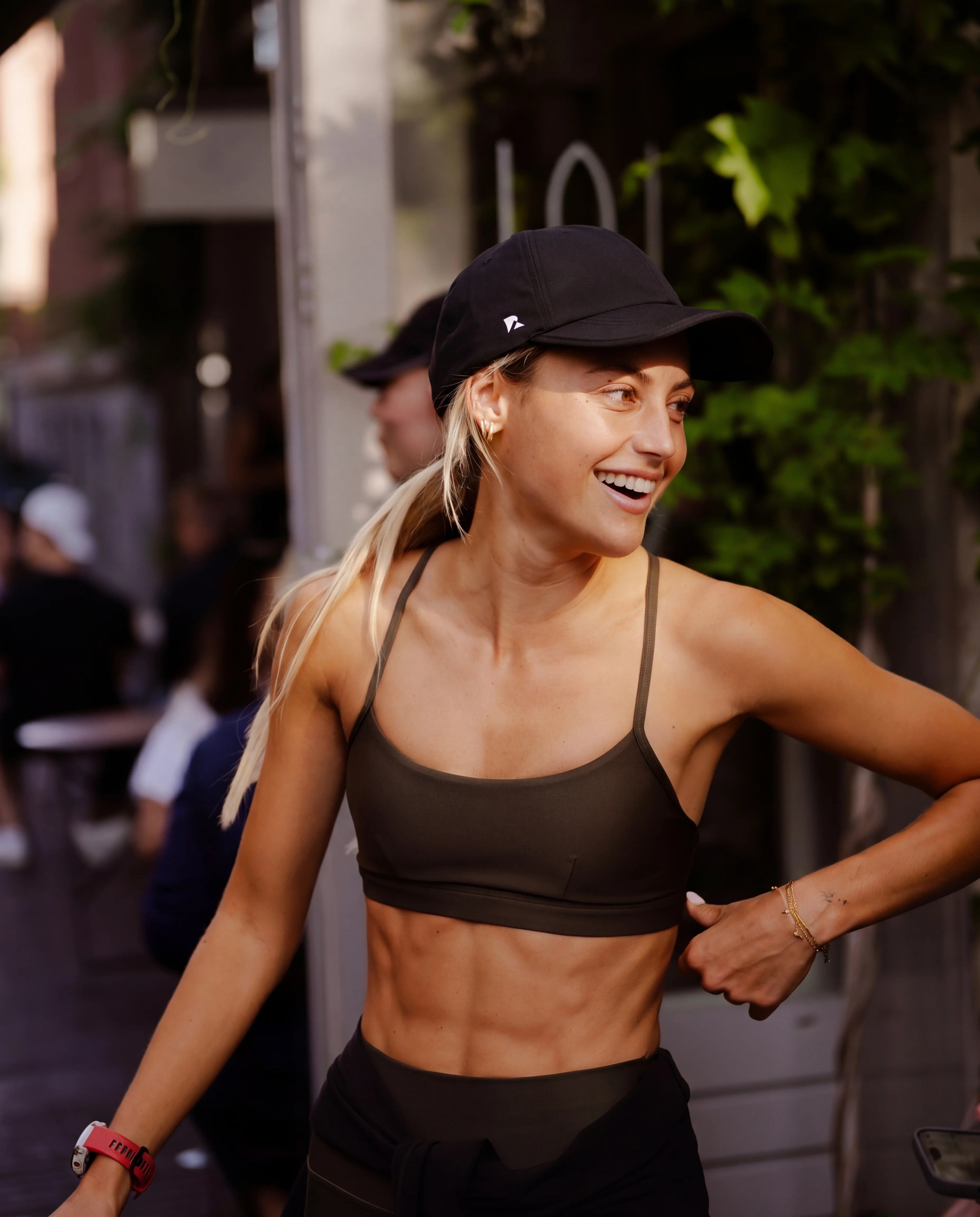 Black running hat worn with olive sports bra outdoor street lifestyle