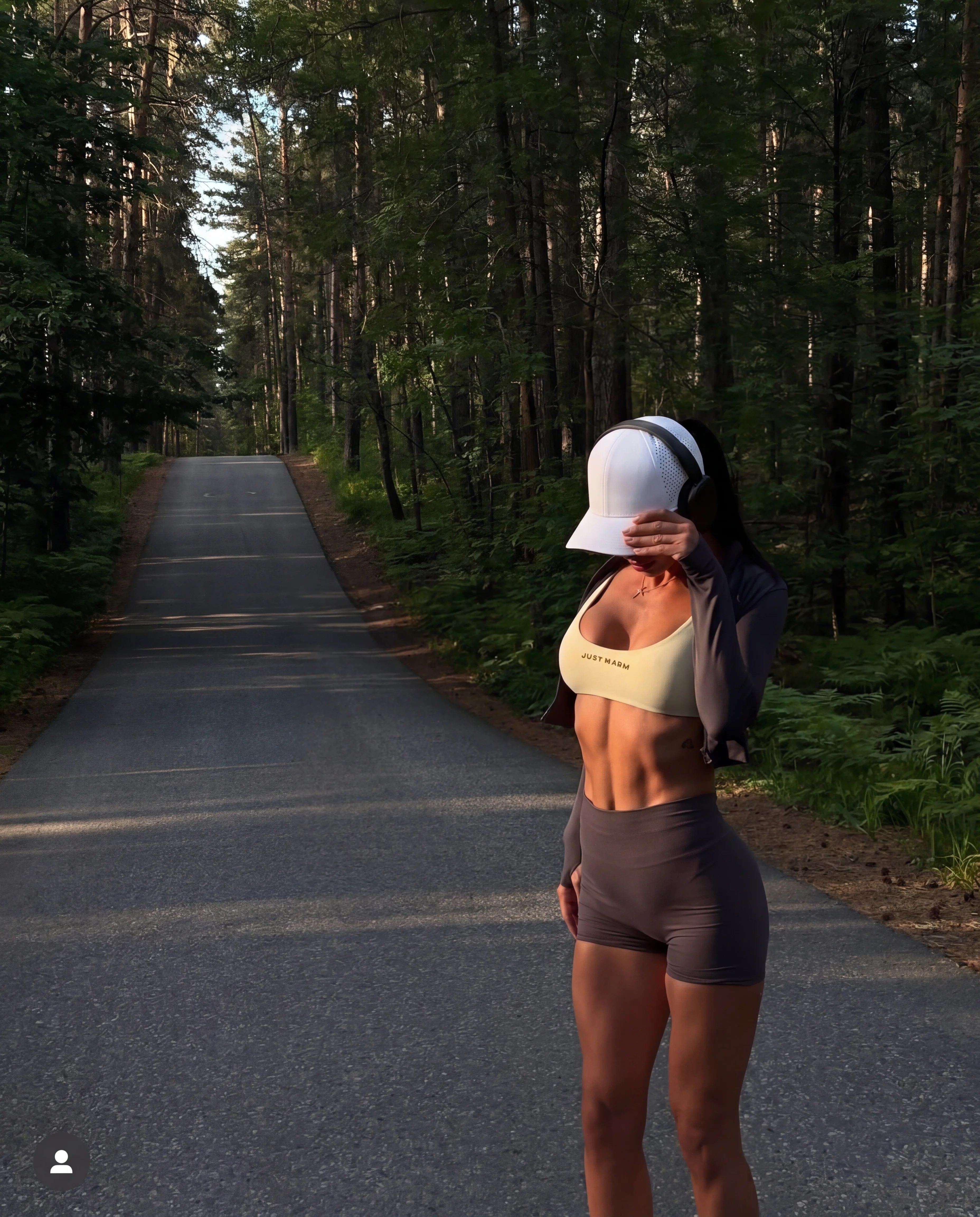 White running hat with sports bra and booty shorts on forest road