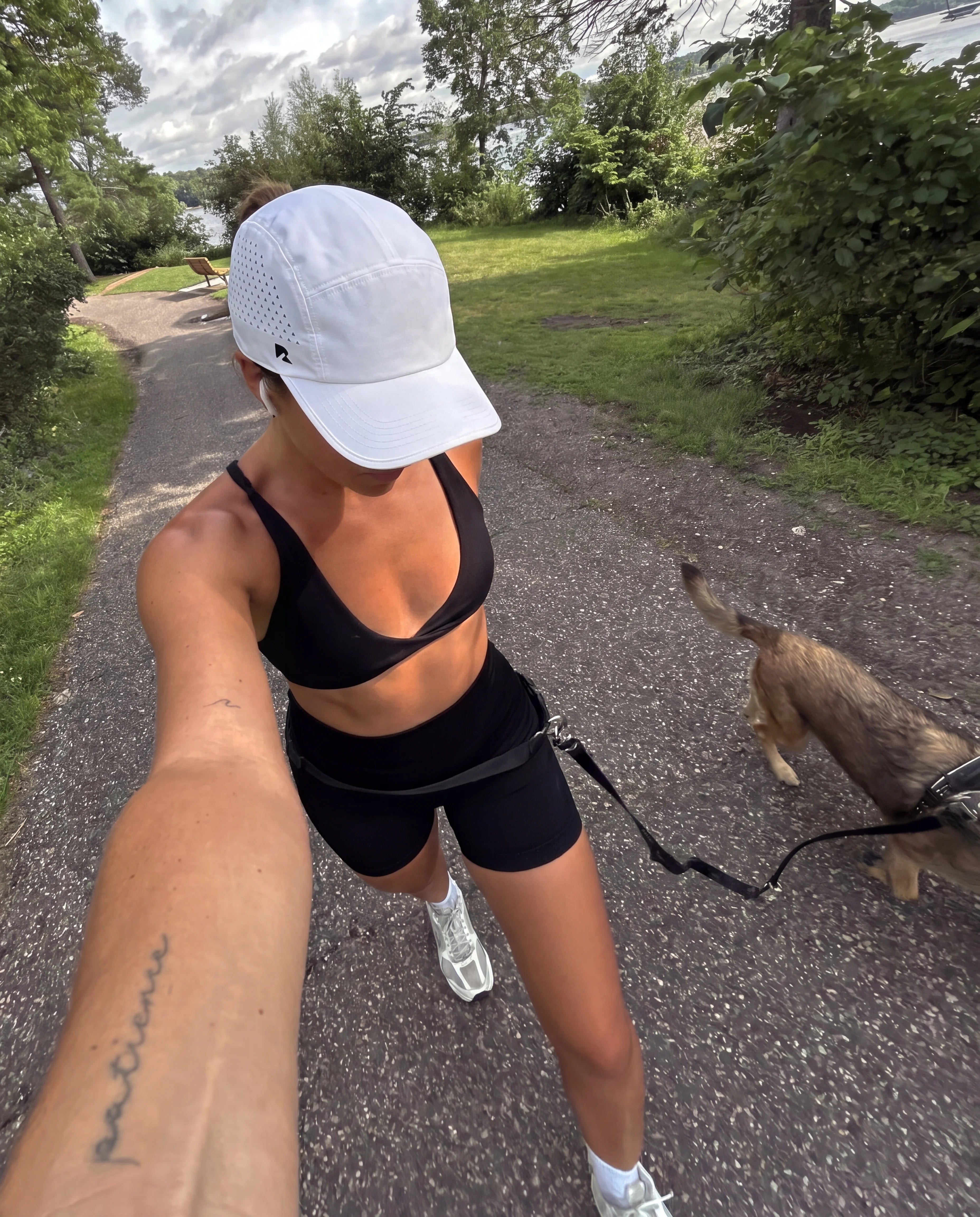 White running hat and black sports bra on park path dog walk