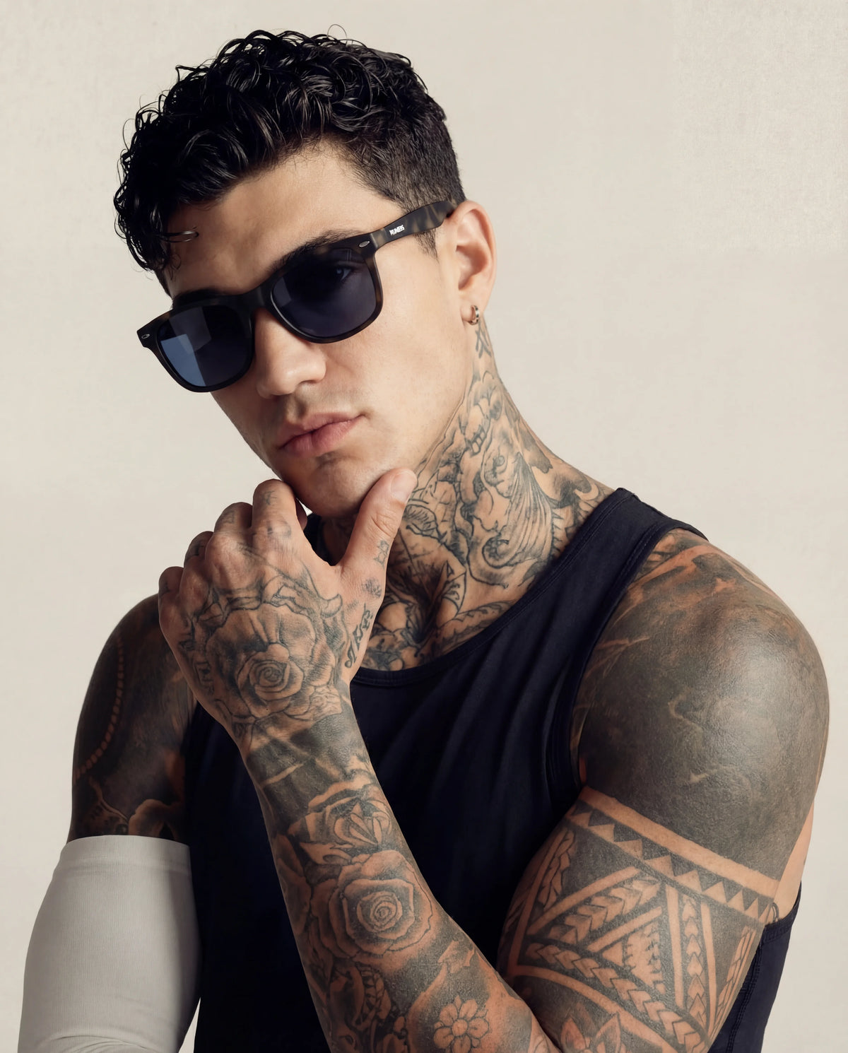 Tortoise shell running sunglasses on tattooed male model black tank