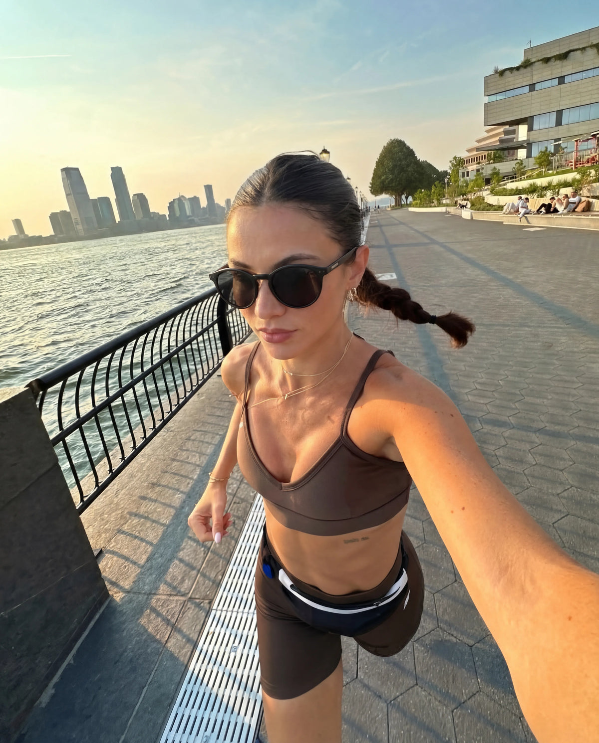 Olympians black round running sunglasses on woman from Runners Athletics running NYC waterfront with city skyline