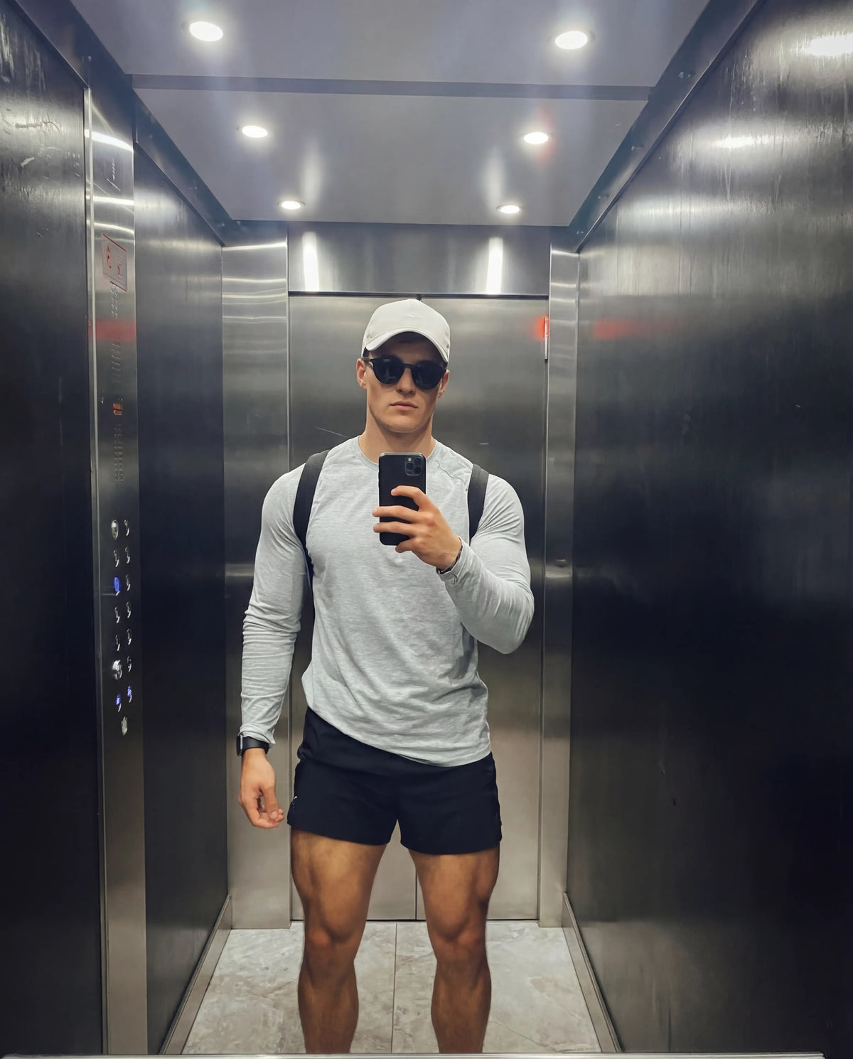 Black round running sunglasses from Runners Athletics on man in grey athletic long-sleeve and white cap
