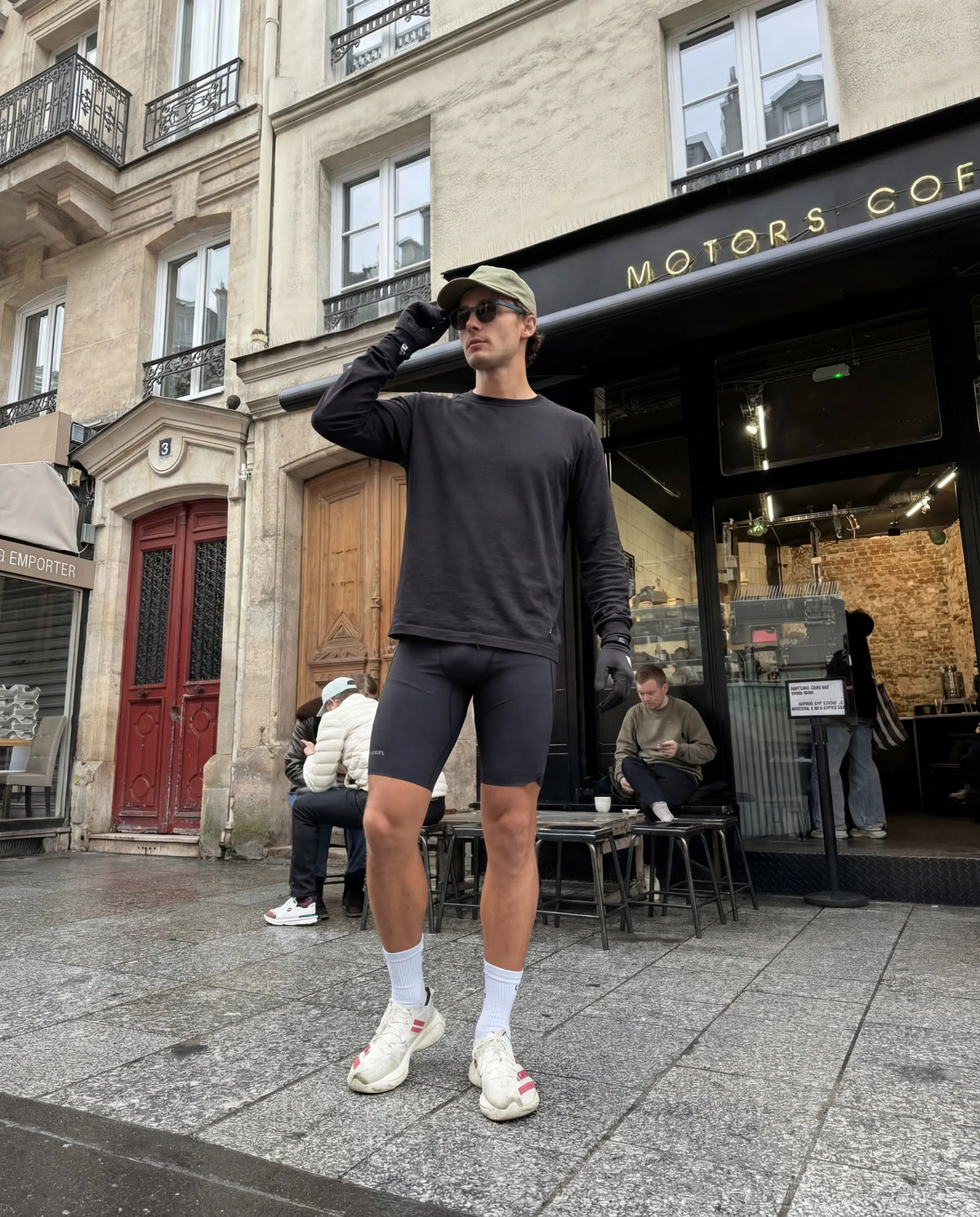 Olympians black running sunglasses from Runners Athletics worn by man on Paris street in athletic outfit