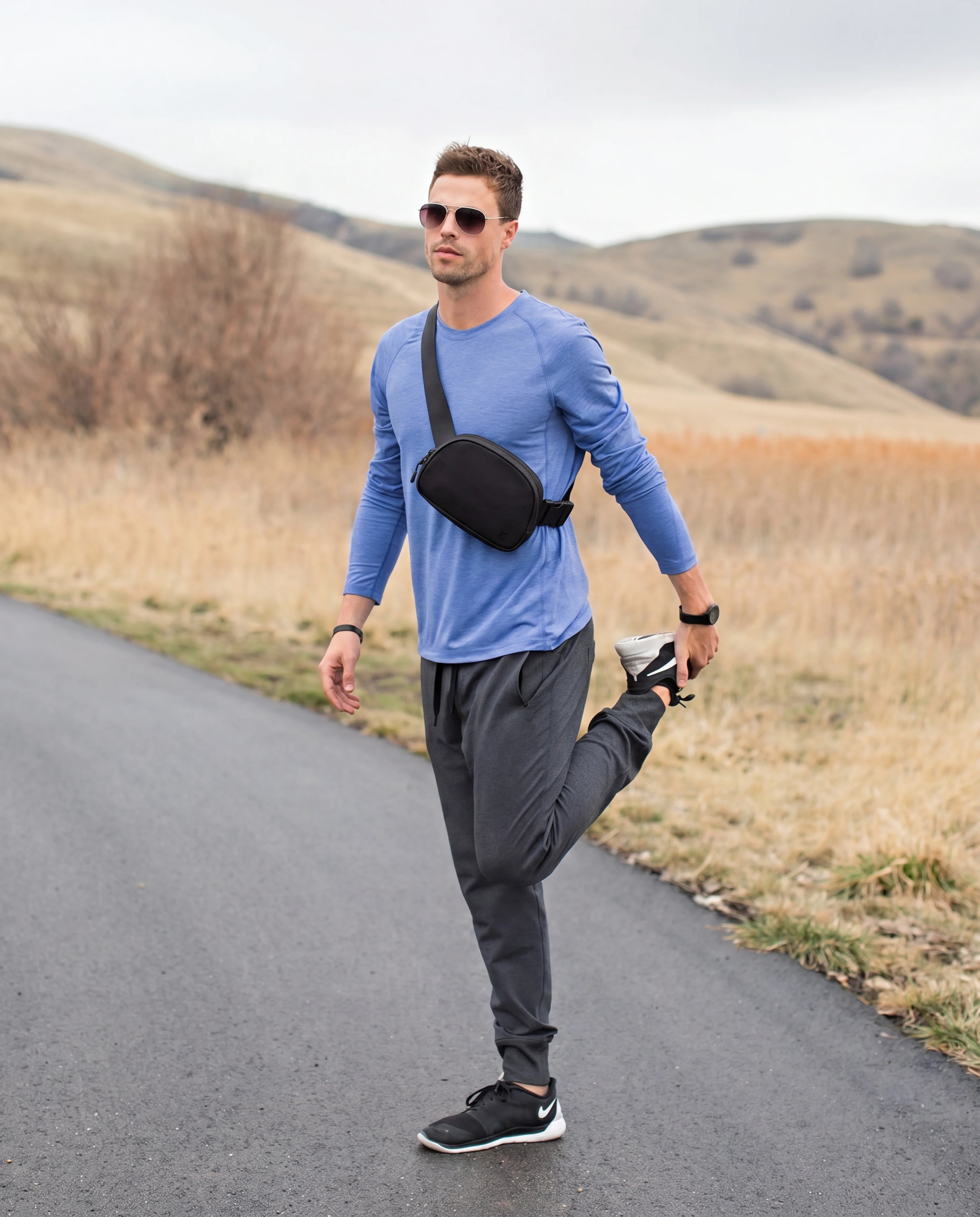 Black crossbody sling bag worn by man on outdoor road run lifestyle