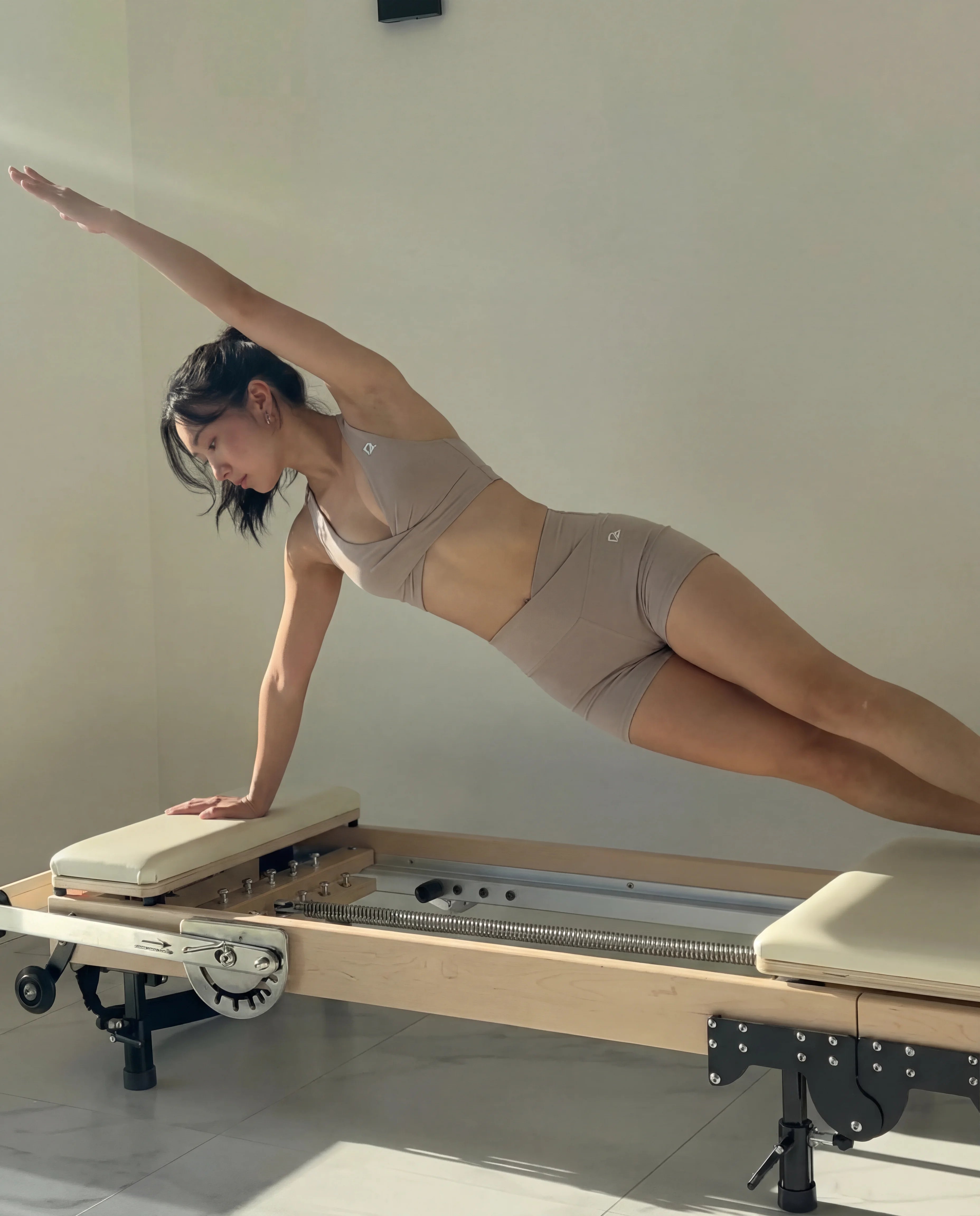 Taupe workout set halter bra and mini sculpting shorts worn on pilates reformer